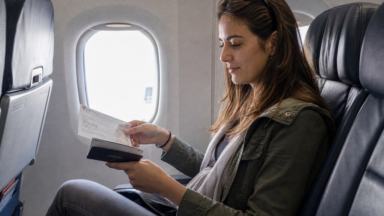 Passenger in an airplane cabin holding travel documents